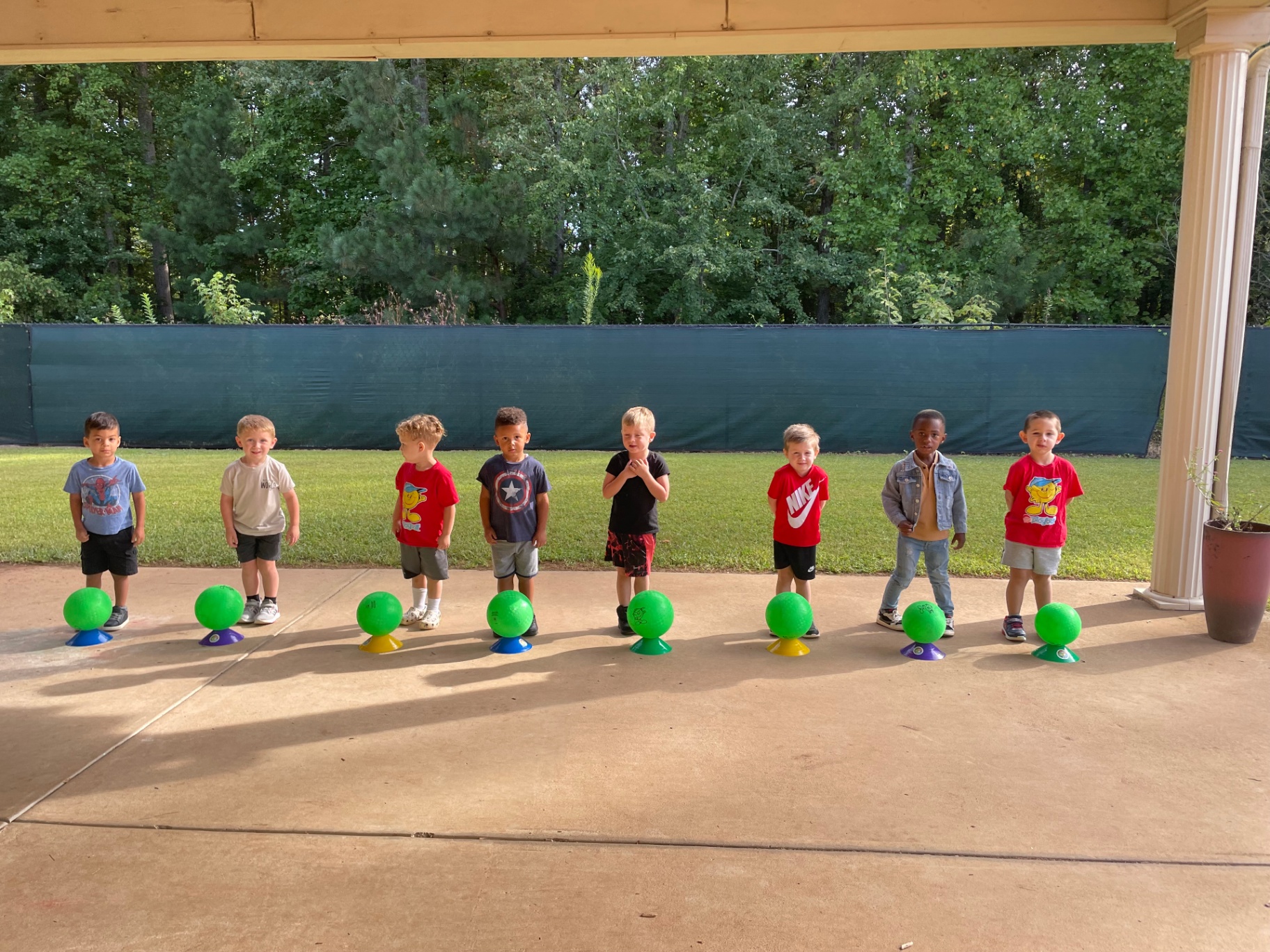 Line of kids with green balls on cones